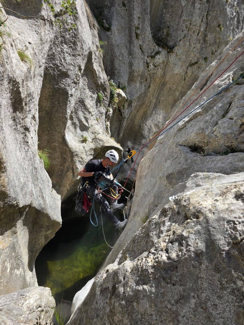 Alpinista na Via Ferrati Brina uspinjući se kroz usku kanjsku prosljedu između stijena