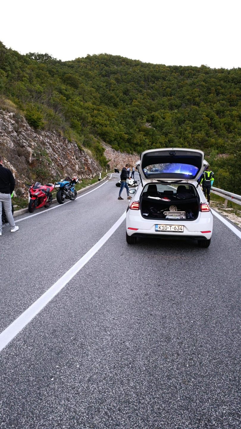 Oštećeni automobil na cesti s policajcima i drugim vozilom u pozadini