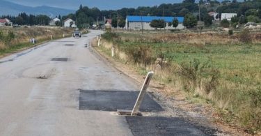 Oštećena asfaltna cesta s provalijom od pukotine poklopca šahte