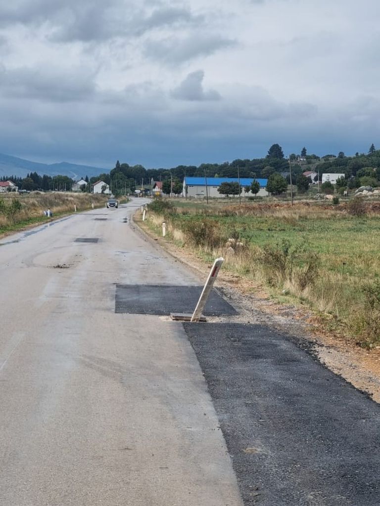 Oštećena asfaltna cesta s provalijom od pukotine poklopca šahte