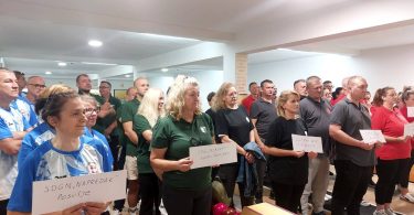 Grupa sudionika natjecanja u kuglanju drži diplome i certifikate u dvorani