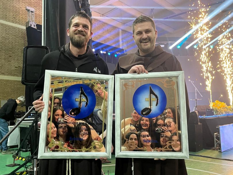 Dva člana Frama Posušja drže dvije nagradne diplome ispred scene sa svjetlosnom dekoracijom