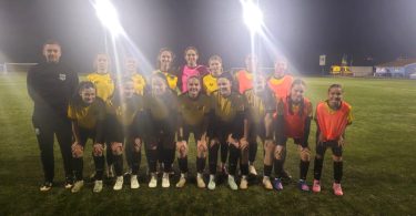 Ženski fudbalski tim Inter pozira za timsku fotografiju na terenu под floodlights