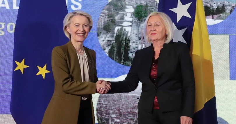 Dvije žene u poslovnom odjelu rukuju se ispred zastava EU i BiH