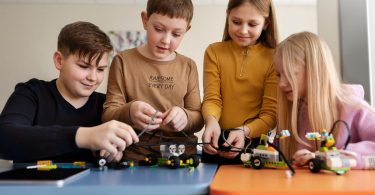 Četiri učenika sastavljaju i programiraju robota na radionici iz robotike