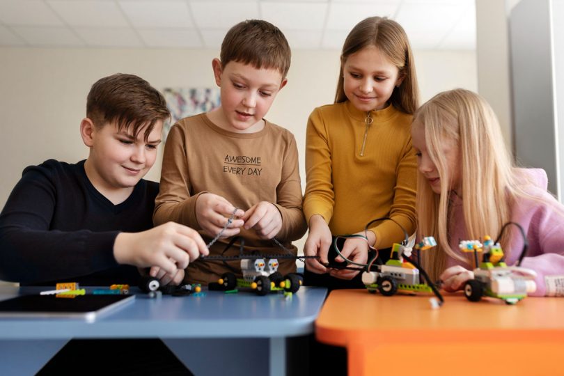 Četiri učenika sastavljaju i programiraju robota na radionici iz robotike