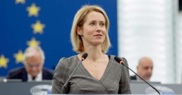 Žena govori za mikrofon pred europskom zastavom u parlamentarnoj dvorani