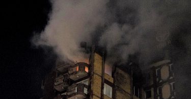 Višekatna zgrada u plamenu s gustim dimom tijekom noćnog požara
