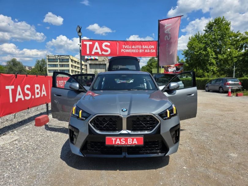 Plavi BMW X2 ispred autosalona TAS s reklamnim баnerima