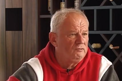 Stariji muškarac u crvenoj i sivoj jakni, emotivnog izraza lica tijekom intervjua