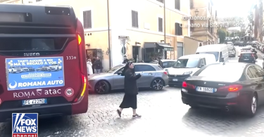 Časna sestra u crnoj odjeći regulira promet između vozila na ulici u Rimu