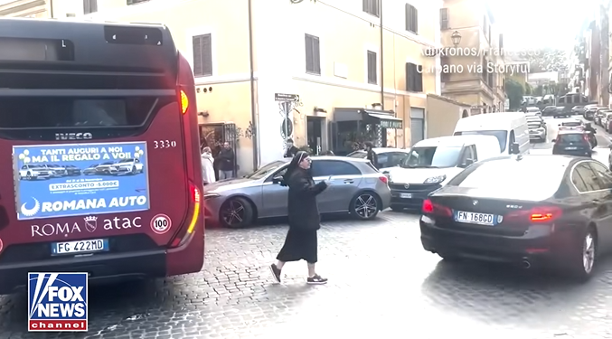 Časna sestra u crnoj odjeći regulira promet između vozila na ulici u Rimu
