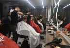 Grupa građana u frizerskom salonu tijekom humanitarnog božićnog šišanja