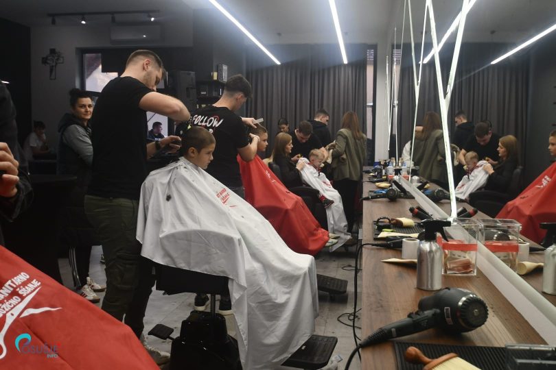 Grupa građana u frizerskom salonu tijekom humanitarnog božićnog šišanja
