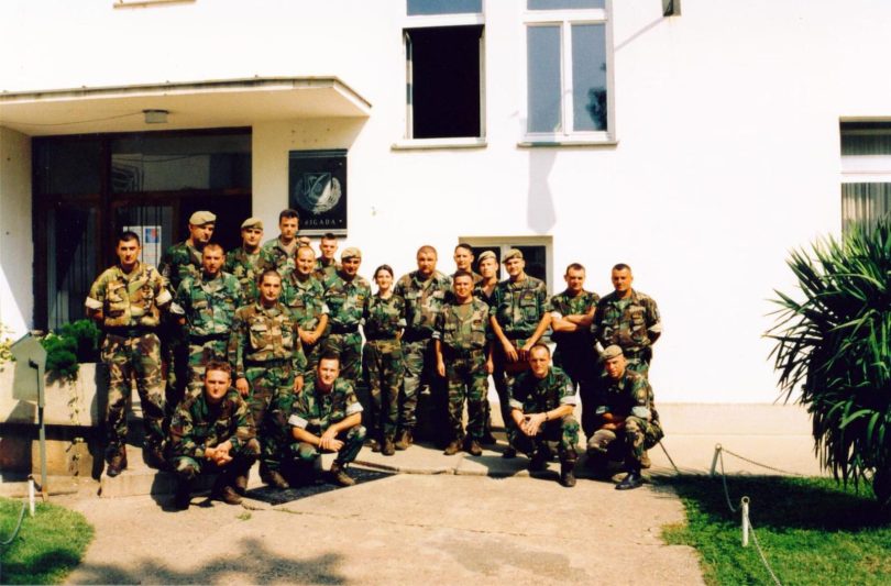 Grupa vojnika u vojnoj uniformi poređana u red ispred zgrade