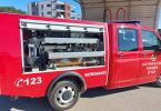 Crveno vatrogasno vozilo s brojem C123 i otvorenim bočnim vratima s opremom