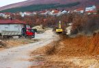 Bager i kamion na gradilištu tijekom radova u zemljanom terenu uz stambene kuće