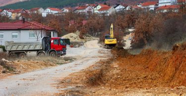 Bager i kamion na gradilištu tijekom radova u zemljanom terenu uz stambene kuće