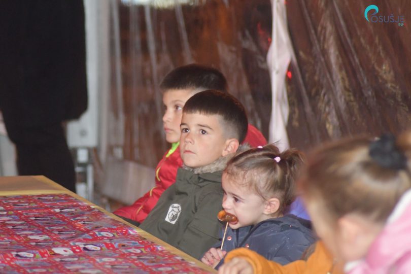 Djeca gledaju prikazanu predstavu tijekom blagdanskog događaja u zatvorenom prostoru