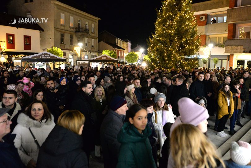 Velika gužva ljudi na noćnom događaju s božičnom светлošću i dekoracijom u gradu