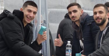 Tri mladića se smiju i poziraju za fotografiju tijekom Badnjaka