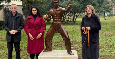 Četiri osobe pored brončane statue Bruce Leea s pločom 'Bruce Lee Tvoj Mostaf'