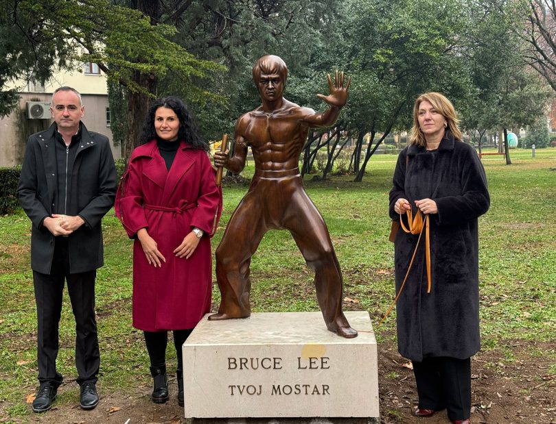 Četiri osobe pored brončane statue Bruce Leea s pločom 'Bruce Lee Tvoj Mostaf'
