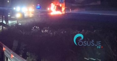 Automobil u plamenu noću, vatrogasci i vozila hitne pomoći na mjestu incidenta