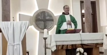 Svećenik u zelenim su ornatem pri oltaru tijekom službe Božje, pozadini križ i svijeće