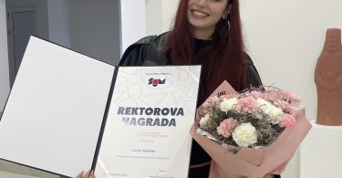 Žena u crnoj odjeći s diplomom i cvijećem, dobitnica univerzitetske nagrade
