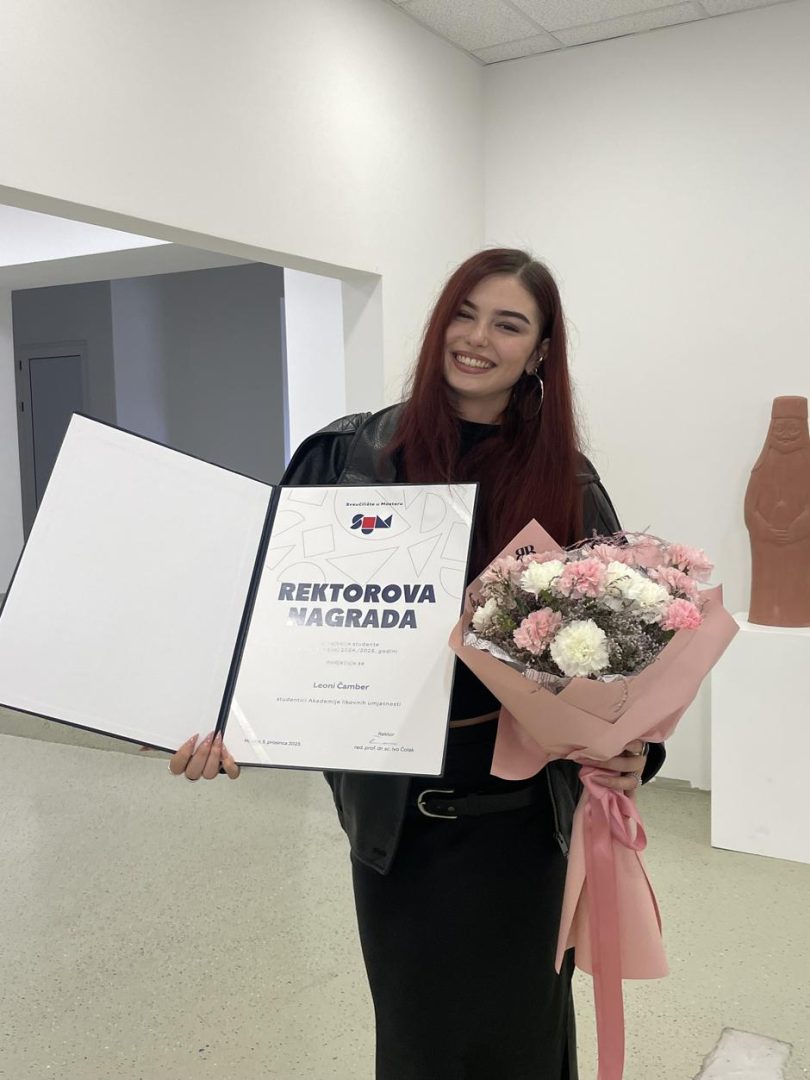 Žena u crnoj odjeći s diplomom i cvijećem, dobitnica univerzitetske nagrade