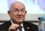 Stariji muškarac u odijelu i naočalama govori tijekom konferencije
