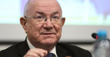 Stariji muškarac u odijelu i naočalama govori tijekom konferencije