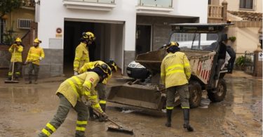 Vatrogasci u žutim odjelima čiste ulicu od šuta nakon poplava
