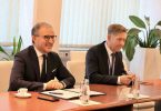 Dva muškarca u poslovnim odijelima za pregovaračkim stolom tijekom formalnog sastanka