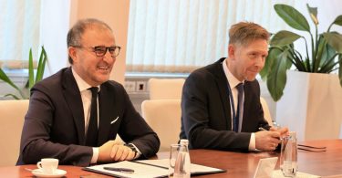 Dva muškarca u poslovnim odijelima za pregovaračkim stolom tijekom formalnog sastanka