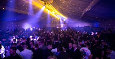 Velika scena s plavim i žutim svjetlima ispunjena gostima tijekom zimskog festivala
