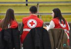 Tri dobrovoljca s crvenokrsnim znakovima čekaju tijekom akcije darivanja krvi