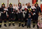 Група vatrogасаца у униформама са осморо новорођене деце позирана за фотографију