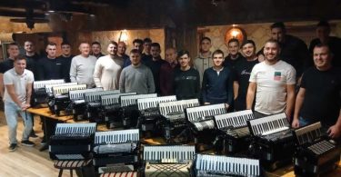 Grupa harmonikaša s harmonikama pozira za fotografiju u dvorani