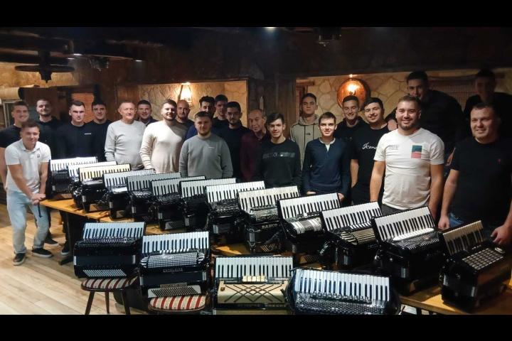 Grupa harmonikaša s harmonikama pozira za fotografiju u dvorani