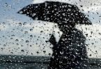 Osoba s kišobranom u jakoj kiši ispred mora