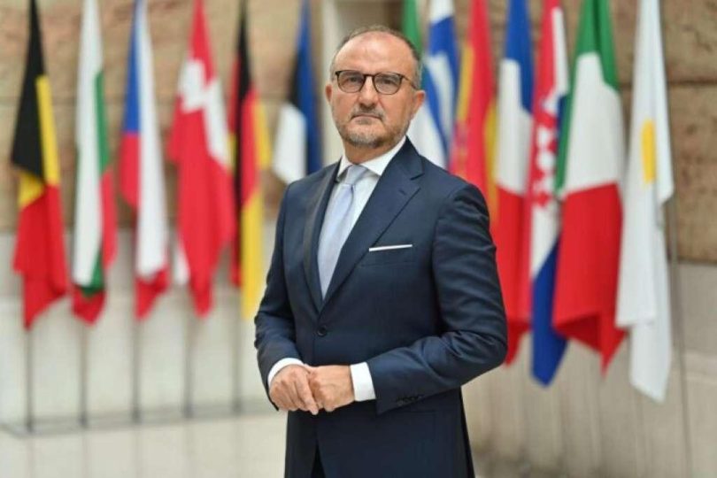 Muškarac u plavom odijelu i naočalama ispred zastava europskih zemalja