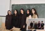 Grupa učenika u crnoj odjeći stoji ispred školske table tokom praktične nastave