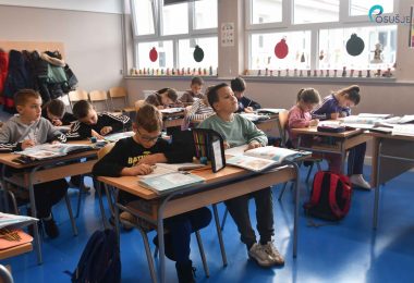 Učenici sjedeći za školskim stolovima tijekom nastave u učionici