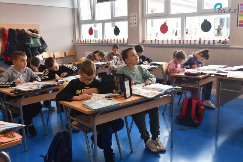 Učenici sjedeći za školskim stolovima tijekom nastave u učionici
