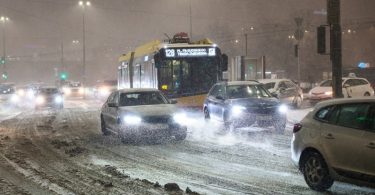 Autobusi i automobili zarobljeni u snježnoj oluji na cesti tijekom noći s uključenim svjetlima