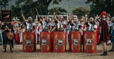 Rimski vojnici u crvenim uniformama i oklopima sa štitovima tijekom Rimskih dana u Mokrom