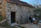 Kamena kuća s drvenim vratima, obnovljena s bijelim namještajem ispred