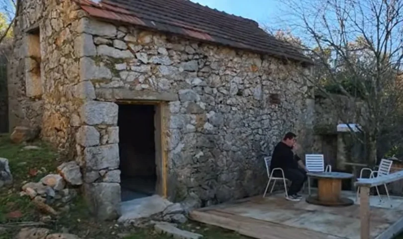 Kamena kuća s drvenim vratima, obnovljena s bijelim namještajem ispred